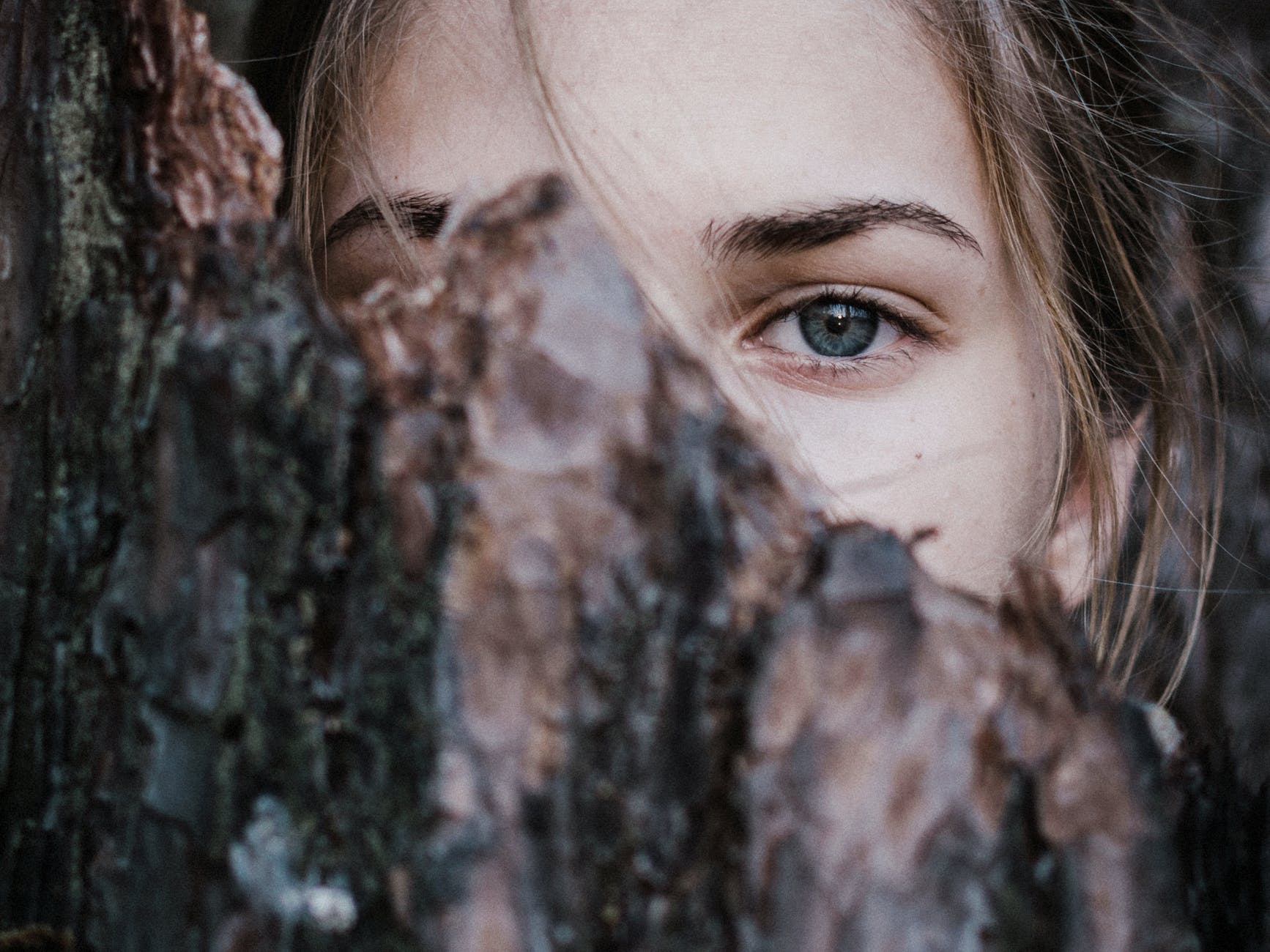 understanding introverts - calm woman behind tree bark in park
